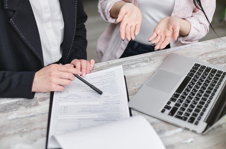 Photo by Mikhail Nilov Two professionals discussing a contract at a business meeting with documents and a laptop.